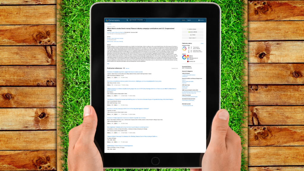 An image of a Dimensions screen showing a paper entitled "Where there's smoke there's money: Tobacco industry campaign contributions and U.S. Congressional voting" on an iPad screen