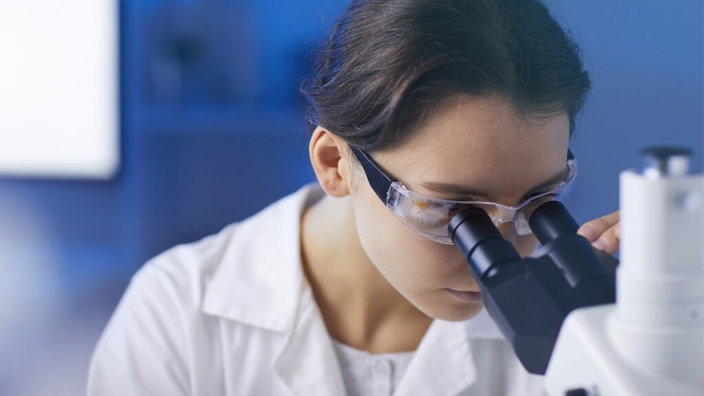 Researcher looking into microscope