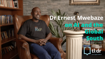 Dr Ernest Mwebaze sits on an armchair in a library