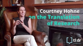 Courtney Hohne sits in an armchair by the fire chatting about translation of research