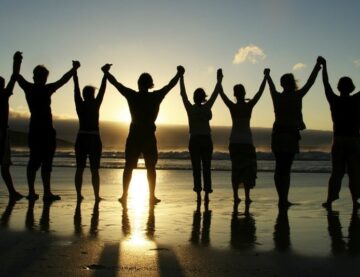 pic of group of people holding raised hand on the beach